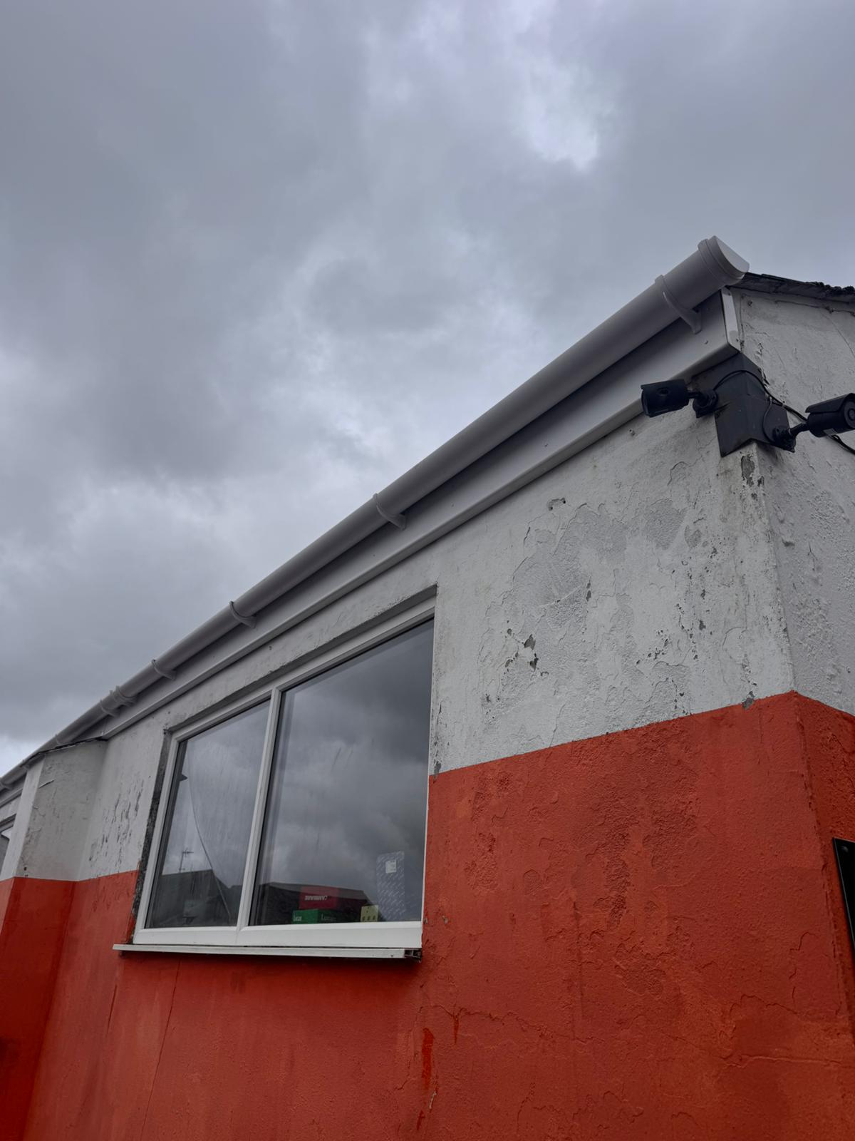 Commercial gutters and downpipes after cleaning — bright white finish